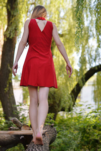 一个穿着红色连衣裙的金发女郎正在公园里散步。