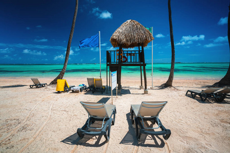 热带海滩上的棕榈树太阳椅和救生站