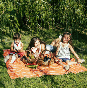 可爱的幸福的家庭野餐铺上绿草的母亲和孩子