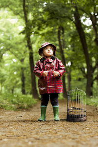小女孩站在森林里寻找失去的鸟儿