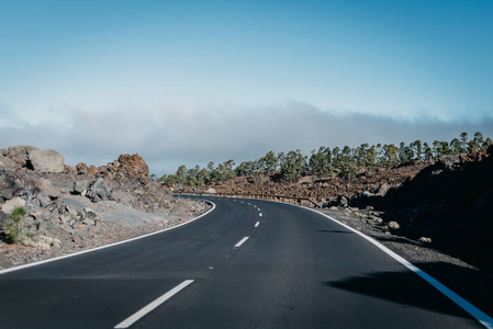 高速公路穿过靠近云层的岩石向左走。Teide 国家公园。特内里费