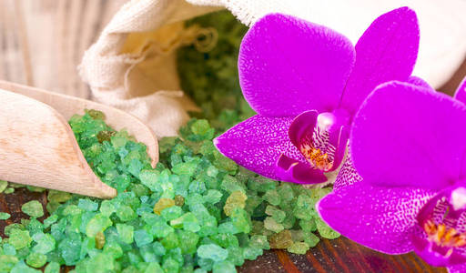 木制表面和兰花的汤匙上的绿色浴盐