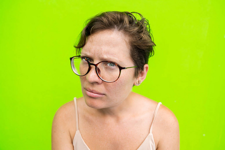 一个戴眼镜的女人的肖像, 看着照相机和一张不愉快的脸。问题和不满