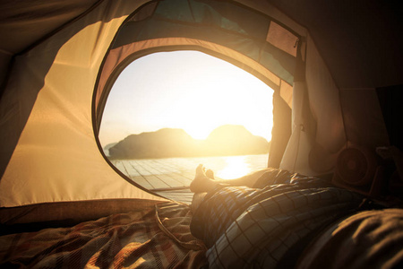 从帐篷露营, 一个男人躺在帐篷与山的看法在上午