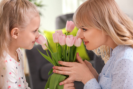 可爱的小女孩和她的母亲的肖像在家里的郁金香花束