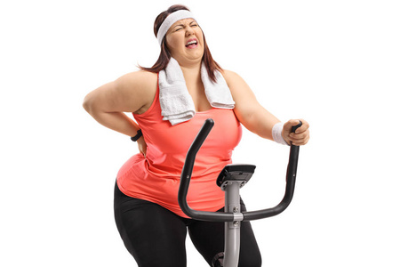 超重妇女骑自行车和经历背部疼痛隔离的白色背景