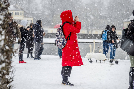 穿红大衣的女士在暴风雪中拍照图片