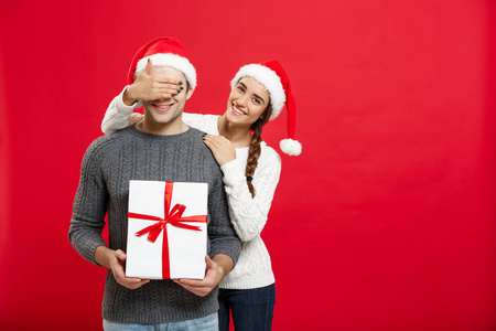 圣诞概念年轻女子用手捂着眼睛, 给人惊喜的大礼物。在红色背景上被隔离