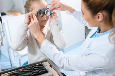 女性眼科医生用试用框架和镜片检查儿童眼睛