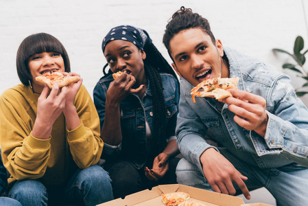 多文化的朋友吃比萨饼和看比赛的微笑的小组
