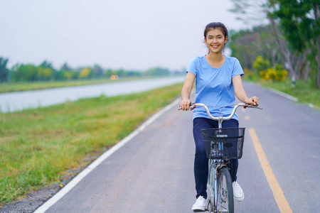 女孩与自行车, 妇女骑自行车在路在公园里