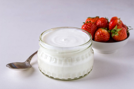 白酸奶在玻璃碗与匙子和 starwberries 在白色背景