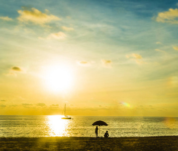 日落时分在海滩上享受度假的人们的剪影