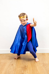 傻笑超级英雄男孩竖起大拇指假装超级激动人心的力量