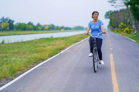 女孩与自行车, 妇女骑自行车在路在公园里