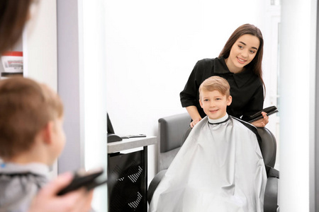 专业女理发师与小男孩在沙龙工作