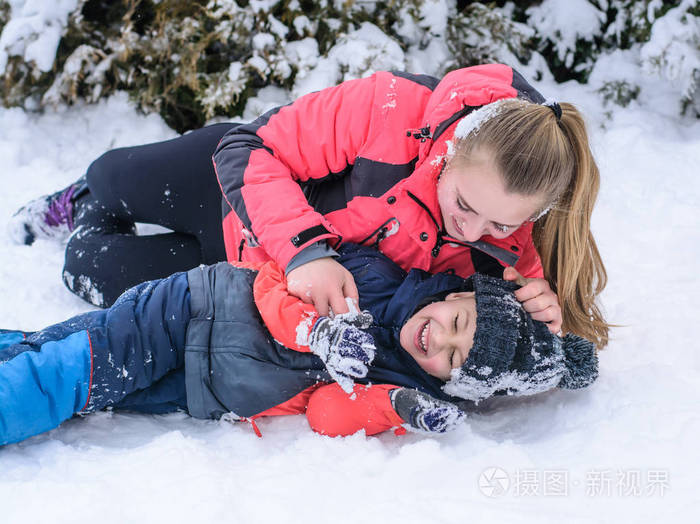 愉快的母亲与她的儿子在胳膊拥抱在雪