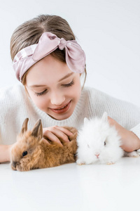 快乐的孩子玩与可爱的毛茸茸的兔子白色