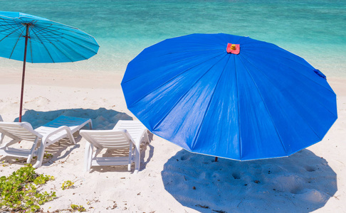 在美丽的热带海滩上的蓝色雨伞。假日概念