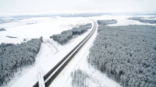 冬天的森林和道路。视图。照片是用无人驾驶飞机拍摄的。雪中的松树和冷杉林