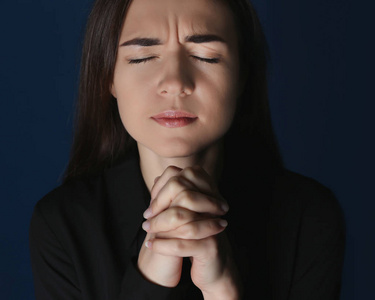 宗教年轻妇女在黑暗背景下祈祷
