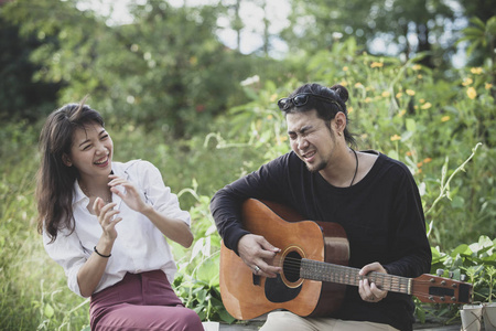 亚洲年轻男子和女吉他与幸福情感