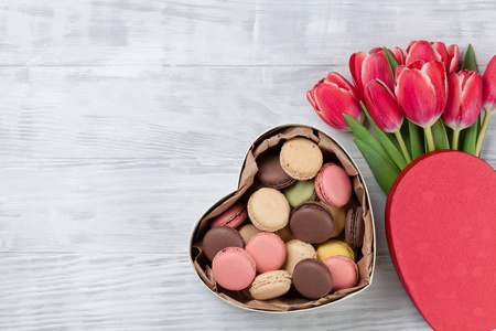 红色郁金香花花束和杏仁在木背景的心形礼品盒。情人节贺卡。带空格的顶部视图
