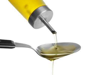 将橄榄油从瓶子倒入勺子上白色背景