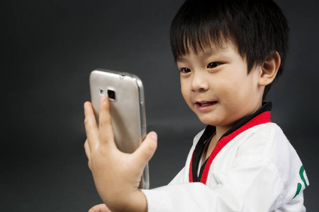 亚洲逗人喜爱的男孩在 karategi 服装拍相片由手机