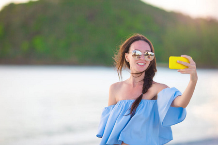 美丽的年轻妇女在热带海滩上自己拍照