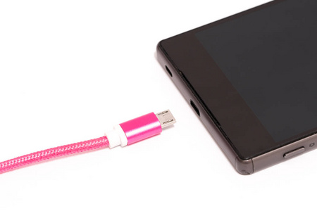 手机充电的概念。粉红色微型 usb 线附近智能手机电源插头。在白色背景上被隔离