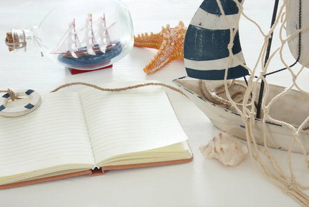 航海概念图片白色装饰风帆小船和空白打开笔记本在白色木桌