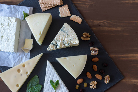 不同种类的乳酪在黑石板用坚果和草本