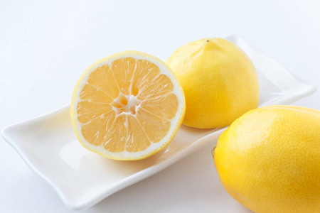 柠檬切成两半。躺在盘子上的柠檬的两半, 躺在旁边的柠檬