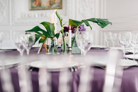 用紫色布在桌子上用玻璃和花朵燃烧蜡烛的成分