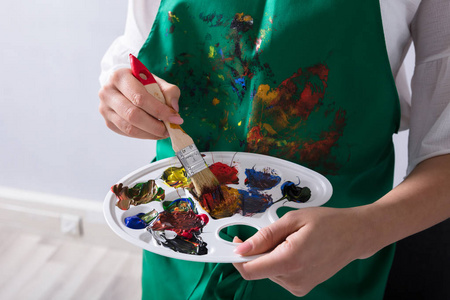 女性艺术家手捧颜料调色板和画笔的中间剖面视图