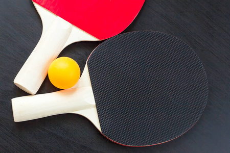 黑色背景下的两个乒乓球或乒乓球拍和球