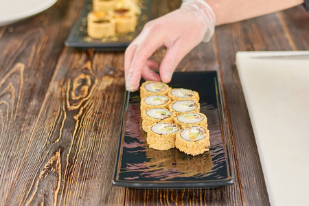 厨师把寿司卷放在盘子里