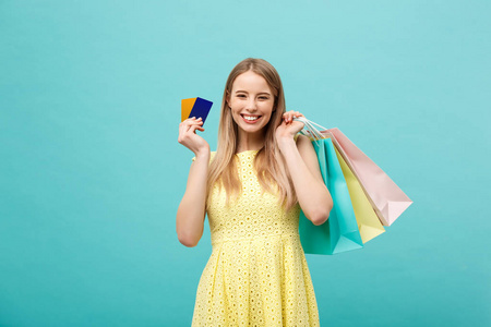 购物和生活方式的概念 美丽的年轻女孩与信用卡和五颜六色的购物袋。在蓝色背景上被隔离