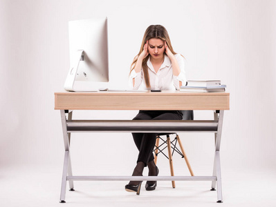 年轻的职业女性强调和疲惫的头痛坐在办公桌上的白色隔离