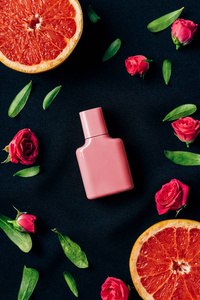 玫瑰花蕾和柚子片上黑色的香水瓶的顶部视图