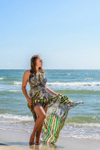 美丽的女孩站在黑海海滩上的太阳镜和礼服