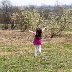 代表春天或自由概念的照片一个小女孩跑在草地上, 她回到相机