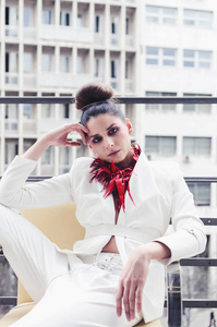 设计师白色西装和红色项链摆在阳台上的年轻女子