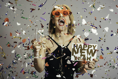 快乐滑稽的金发女郎庆祝新年与香槟和新年标志