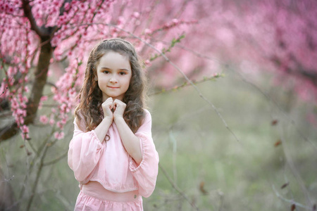 美丽的小女孩在花园里, 反对开花的树木摆在户外