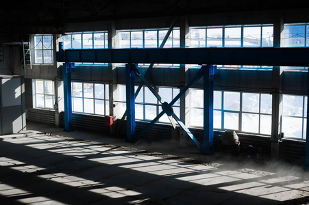 制造工厂。空机库大楼。蓝色色调背景。具有大窗户和金属结构的生产室