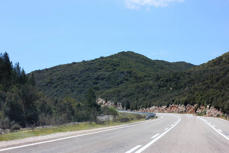 狭窄的山沥青路。蓝色夏日天空