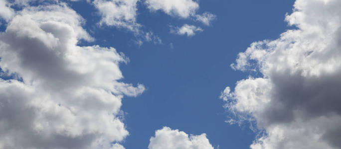蓝天上有许多不同大小的白云, 在万里无云的地方形成了一个框架。