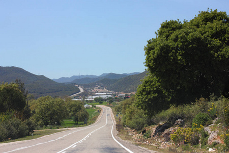 狭窄的山沥青路。蓝色夏日天空